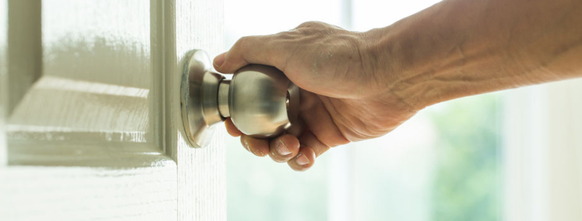 Photo of a hand turning a door knob.
